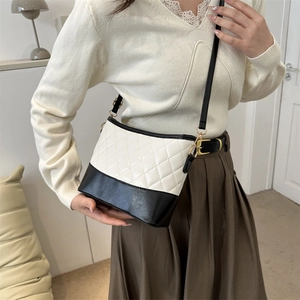 Chic black and white crossbody bag with quilted diamond pattern on a female model