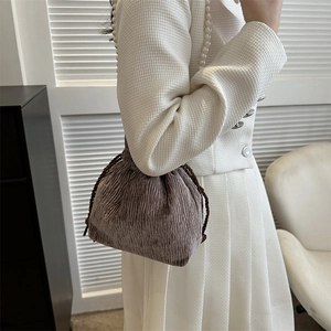 Detailed view of dark brown pleated drawstring bag with decorative white pearl strap
