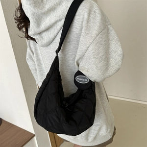 Quilted black half-moon crossbody bag shown on model with adjustable wide strap