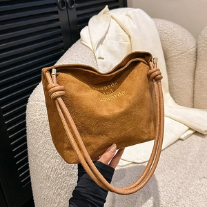 Detail of brown suede tote bag with yellow embroidery and unique knot handle design