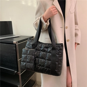 Detailed view of black quilted tote bag with matching zippered coin purse and woven handles