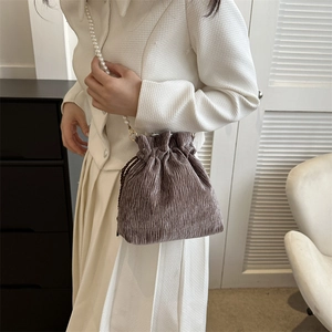 Detail of purple pleated drawstring bag with luxury white pearl chain strap on model