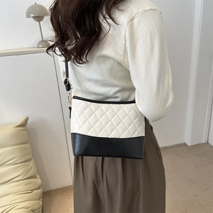 Detail showing monochrome quilted PU leather bag worn by model in a home setting