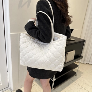 Vue latérale d'un grand sac cabas blanc matelassé porté, montrant sa texture bouffante