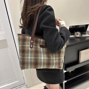 Close-up of winter wool tote bag with green plaid pattern and brown leather straps