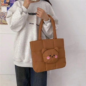 Detail of brown quilted nylon tote bag with a cute 3D plush bear head decoration