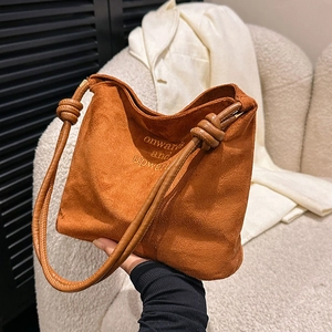 Detailed close-up of brown suede crossbody bag with printed onward and upward text