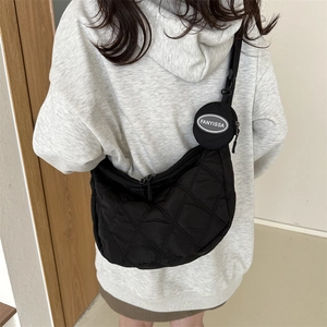 Detail of black quilted crossbody bag with a round coin pouch on the strap