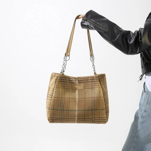 Detail of wool-like fabric texture on brown plaid tote bag with silver chain straps