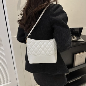 Detailed view of a white quilted PU leather shoulder bag worn by a model in office