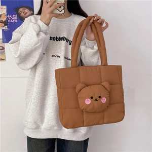 Detailed view of brown quilted tote bag featuring a cute 3D plush bear head decoration