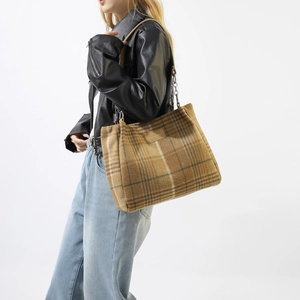 Detail of vintage wool plaid tote bag featuring metal chain and brown leather strap design