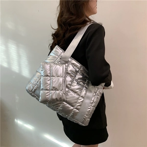 Silver quilted tote bag and matching pouch shown on shoulder with wide fabric strap