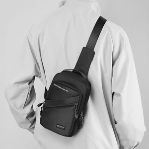 Detail of a black nylon chest bag with adjustable strap and front zipper compartments