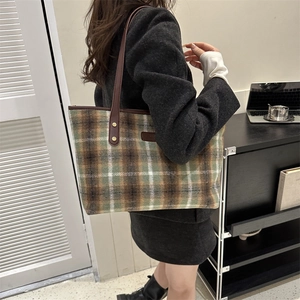 Close-up of vintage plaid wool tote bag with premium leather straps and gold rivets