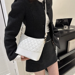 Lifestyle shot of woman wearing quilted white PU crossbody bag in modern office setting