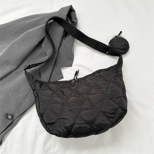 Detail of black quilted nylon crossbody bag with small round coin pouch on a grey suit