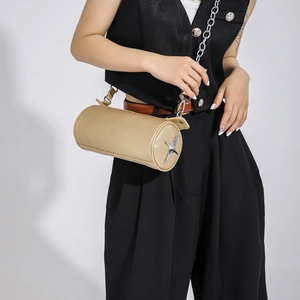 Detail of champagne gold cylinder bag with silver star and lychee grain leather texture