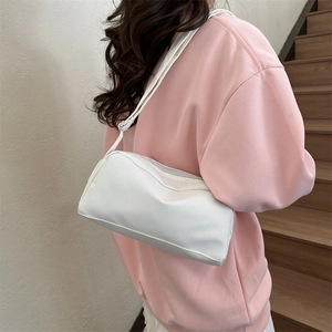 Minimalist white crossbody bag with matte finish shown on model in a cozy home setting