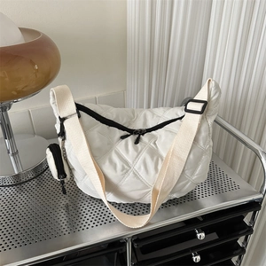 Detail of white quilted crescent bag with adjustable strap and small round coin purse