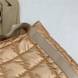 Detailed close-up of light gold quilted puffer tote bag with wide textured strap