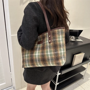 Green and brown plaid wool tote bag with leather straps on model in office setting