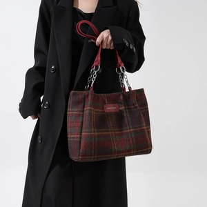 Detail of red and green plaid wool handbag with leather handle and fashion label