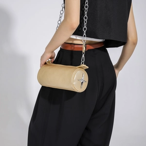 Close-up of golden cylinder handbag with silver star detail and metal chain strap