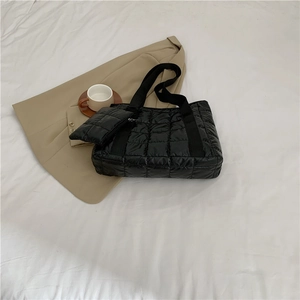 Detail of black quilted tote bag with matching coin purse on a minimalist white backdrop