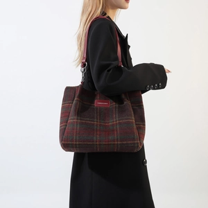 Classic red and green plaid wool tote bag with red leather straps on a model side view