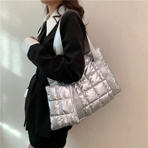 Silver quilted tote bag in metallic finish with stylish wide shoulder strap on model