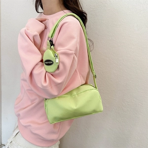 Detail of light green nylon crossbody bag with matching round pouch and wide fabric strap
