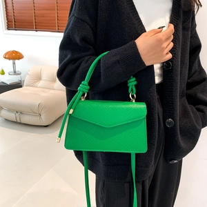 Borsa a tracolla in pelle testurizzata verde con manico a nodo e dettagli dorati su modella