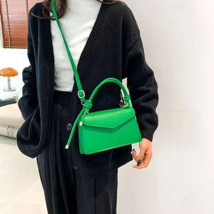 Dettaglio borsa in pelle martellata verde brillante con manico annodato e tracolla regolabile