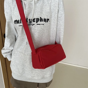 Detail view of a red minimalist nylon crossbody bag with a wide fabric shoulder strap