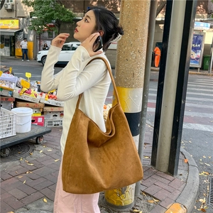 Street style shot of a large brown suede tote bag with minimalist wide shoulder strap