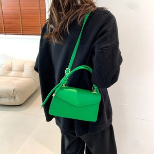 Dettaglio della borsa verde brillante in pelle martellata con finiture in oro su cappotto
