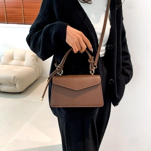 Dettaglio della borsa marrone in pelle martellata con manico annodato sulla spalla