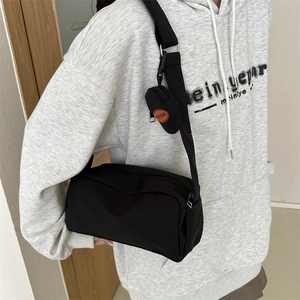 Detail of black crossbody bag with adjustable strap and small detachable Fanyissa pouch