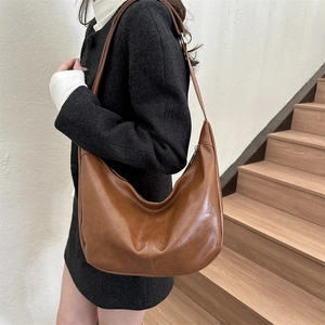 Close-up of a brown hobo bag in glossy faux leather with seamless stitched accents
