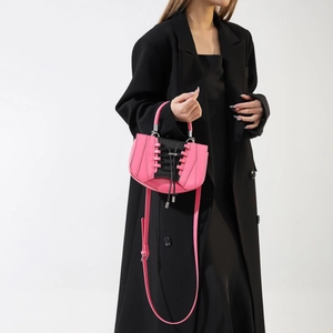 Detail of pink crossbody bag with black lace-up corset design and silver metal handle
