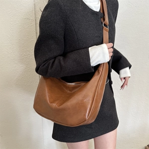 Brown retro crossbody crescent bag with wide strap worn by a model in a modern style