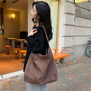 Macro detail of large brown faux suede tote bag showing soft texture and draped shoulder style
