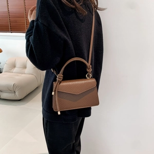 Vista laterale di una borsa marrone in pelle martellata con manico a nodo e tracolla sottile