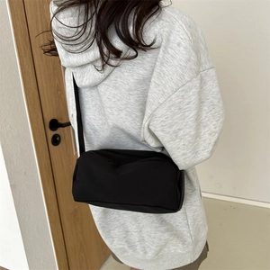 Detail shot of a minimalist black crossbody bag in matte nylon on a model