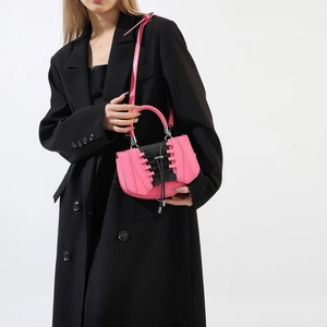Detail view of pink crossbody bag with black lace-up corset design on black coat