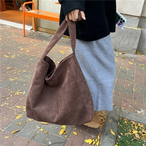 Detail of a large brown suede hobo tote bag featuring minimalist slouchy design and wide strap