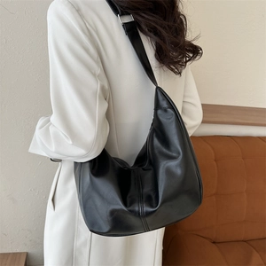 Detail of black PU leather crescent bag with soft pleated texture and adjustable strap