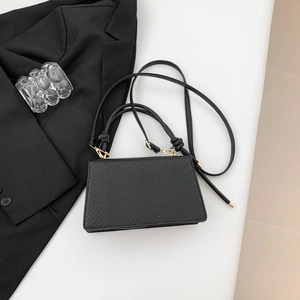 Dettaglio della borsa in pelle PU nera con trama a litchi e finiture in metallo dorato