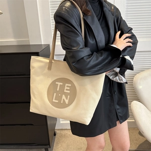Detail showing high-quality canvas tote bag with leather strap and TE LN leather patch logo